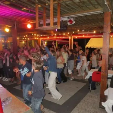 Groupe dansant sous un toit en bois avec éclairage festif, Camping du Lac de Moselotte