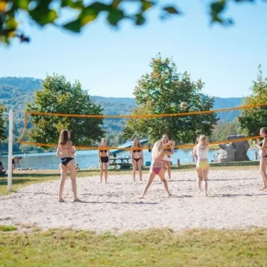 Jeunes filles jouant au beach volley sur le sable du Camping du Lac de Moselotte.