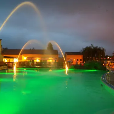 Piscine éclairée en vert avec fontaines lumineuses au Camping Domaine les Fleurs d'Agde