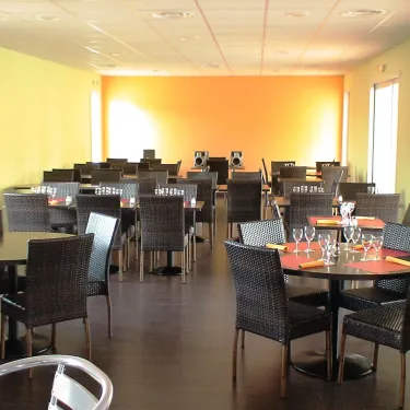 Salle à manger du Camping Domaine les Fleurs d'Agde avec tables et chaises noires