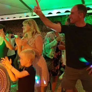 Famille et enfants dansant sous les lumières du camping.