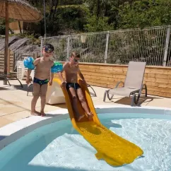 Enfants qui descendent une slide dans la piscine à Camping Coeur d'Ardèche