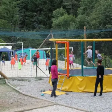 Enfants sautent sur un trampoline dans le parc du camping Coeur d'Ardèche