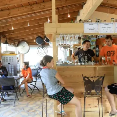 Bar intérieur du Camping Coeur d'Ardèche avec clients et serveurs.