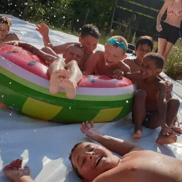 Enfants qui rient sur un tube de glisse en forme de pastille de melon à Camping Coeur d'Ardèche