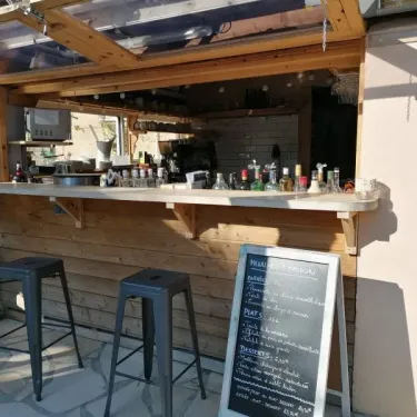 Bar en bois avec tabourets et menu au Camping Coeur d'Ardèche
