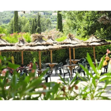Camping Domaine des Naiades : tables et chaises sous parasols en paille