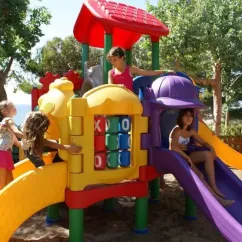 Enfants jouent sur un parc infantile coloré près de la plage au Camping Le Clos de Banes.