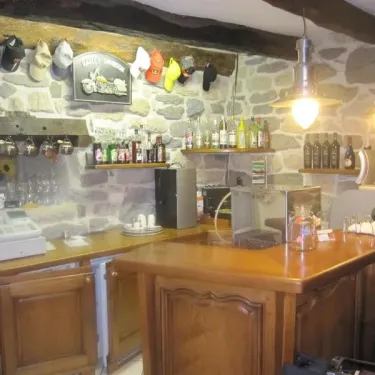 Bar intérieur en pierre avec étagères de bouteilles, lampes suspendues et accessoires décoratifs