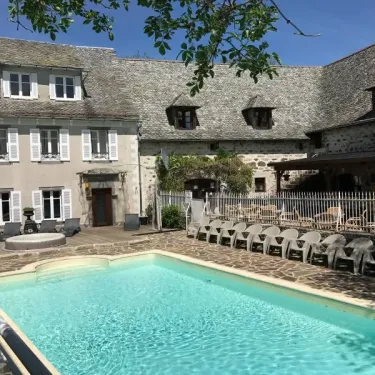 Piscine et piscine en plein air au Camping Le Clos de Banes, entourée d'une maison traditionnelle.