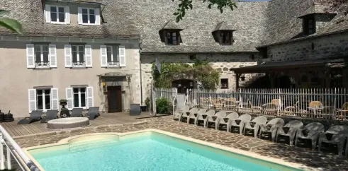 Piscine et piscine en plein air au Camping Le Clos de Banes, entourée d'une maison traditionnelle.