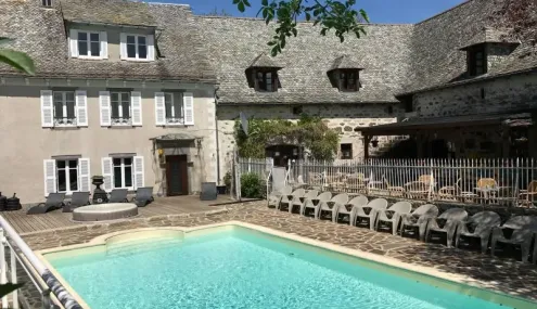 Piscine et piscine en plein air au Camping Le Clos de Banes, entourée d'une maison traditionnelle.