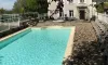 Piscine extérieure du Camping Le Clos de Banes avec bord de piscine en pierre et chaises longues.