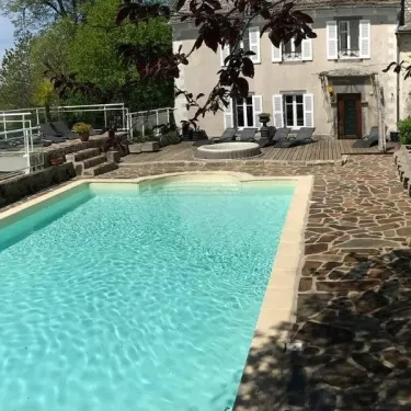 Piscine extérieure du Camping Le Clos de Banes avec bord de piscine en pierre et chaises longues.