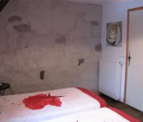 Chambre Quadruple - Le Clos de Banes : chambre avec deux lits et mur texturé.