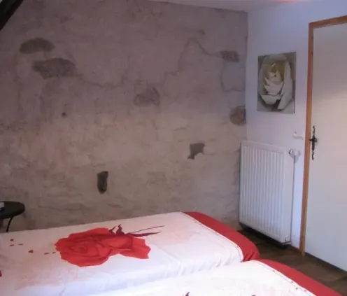 Chambre Quadruple - Le Clos de Banes : chambre avec deux lits et mur texturé.