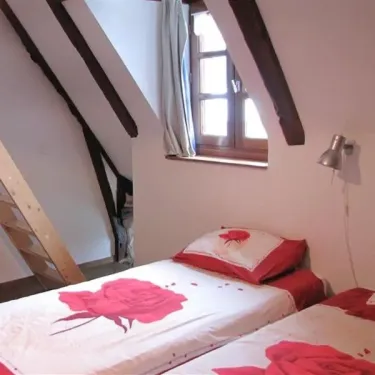 Chambre Quadruple Le Clos de Banes : lits avec motifs roses, poutres en bois, fenêtre