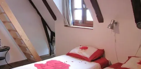 Chambre Quadruple Le Clos de Banes : lits avec motifs roses, poutres en bois, fenêtre