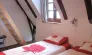 Chambre Quadruple Le Clos de Banes : lits avec motifs roses, poutres en bois, fenêtre