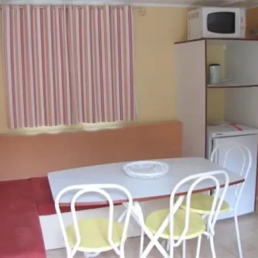 Mobil Home 3 Chambres - 6 personnes - Le Clos de banes : salle à manger avec table, chaises et réfrigérateur