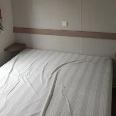 Chambre avec lit double et tête de lit en bois - Mobil Home 2 Chambres - Le Clos de banes