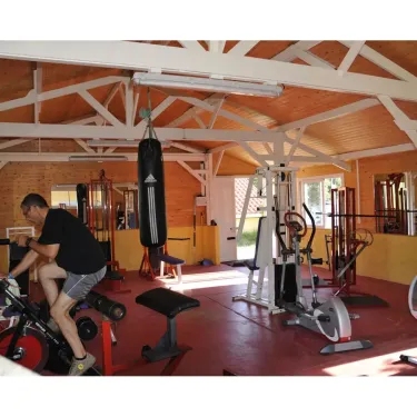 Un homme fait du vélo d'entraînement dans la salle de sport du Camping La Pointe.
