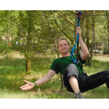 Un homme riant pendant un zip-lining dans la forêt environnante du Camping La Yole.