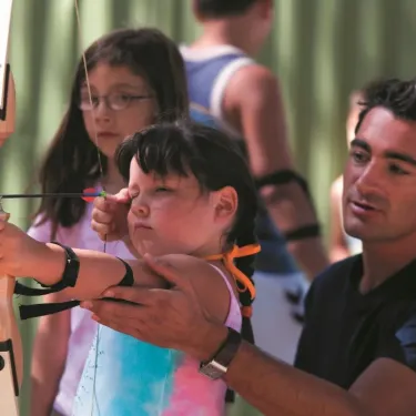Enseignement d'archerie par un adulte auprès d'une enfant au Camping Le Castellas.