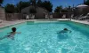 Camping de la Gères - piscine avec enfants nageant sous un ciel bleu