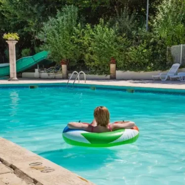 Personne flottant sur un anneau gonflable dans la piscine du Camping Les Bö-Bains.
