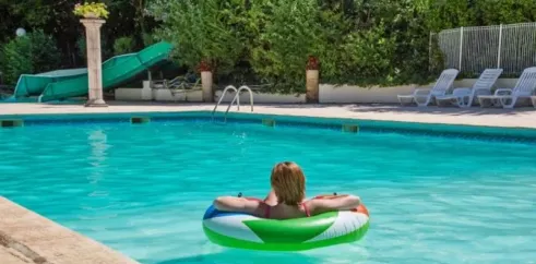 Personne flottant sur un anneau gonflable dans la piscine du Camping Les Bö-Bains.
