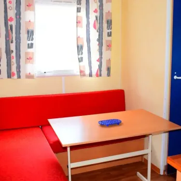Mobil Home 20m² - 1 Chambre - 2/4 Pers. - Le Val d'Hérault : canapé rouge, table en bois