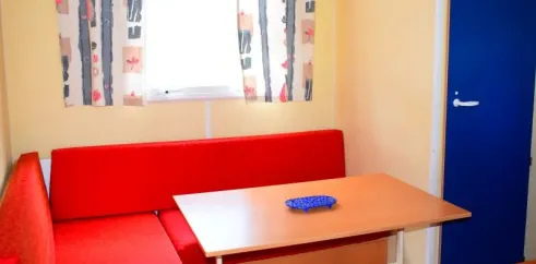 Mobil Home 20m² - 1 Chambre - 2/4 Pers. - Le Val d'Hérault : canapé rouge, table en bois