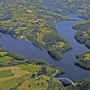 Vue aérienne du lac entouré de collines et de champs à Camping La Romiguière