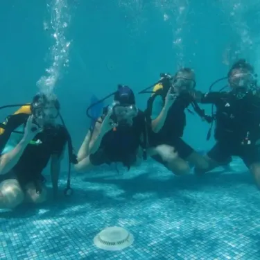 Quatre personnes en plongée sous-marine dans une piscine à Camping La Romiguière.