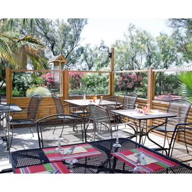 Terrasse extérieure avec tables et chaises métalliques au Camping Le Pré Catalan