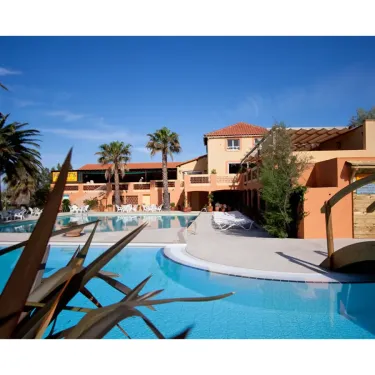 Piscine entourée de palmiers et de bâtiments du Camping Le Pré Catalan