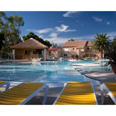 Piscine avec chaises longues jaunes et cabane en paille au Camping Le Pré Catalan