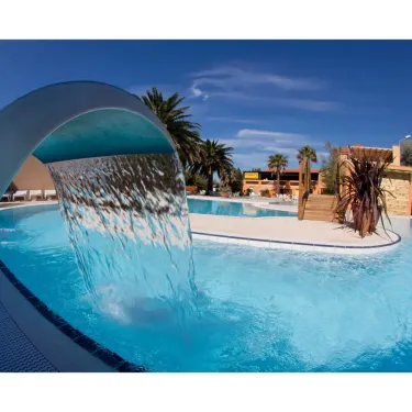 Piscine avec chute d'eau et palmiers au Camping Le Pré Catalan