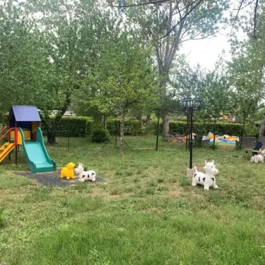 Parc infantile avec toboggan, chevaux en plastique et structures de jeux à Camping Saint-Lazare