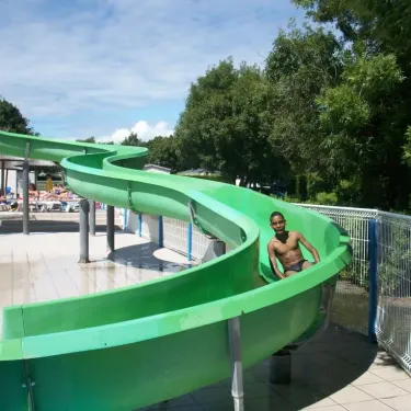 Enfant sur un toboggan vert dans le parc aquatique du Camping Oléron Loisirs.