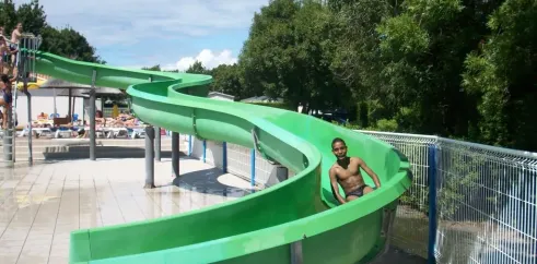 Enfant sur un toboggan vert dans le parc aquatique du Camping Oléron Loisirs.