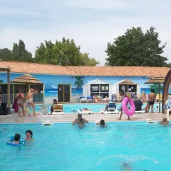 Piscine animée au Camping Oléron Loisirs avec des visiteurs et des flotteurs colorés.