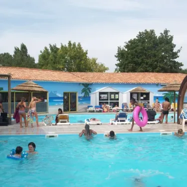 Piscine animée au Camping Oléron Loisirs avec des visiteurs et des flotteurs colorés.
