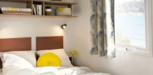Chambre avec lit double, rideau et étagère - MH Confort 3CH - Camping du Lac de La Thésauque