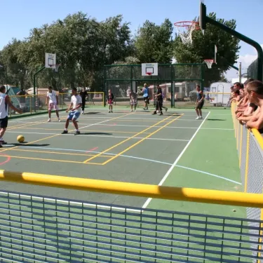 Enfants jouent au basket-ball sur un terrain extérieur dans le camping.