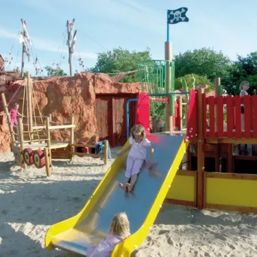 Enfant glisse sur une slide pirate dans le parc d'attractions du camping.