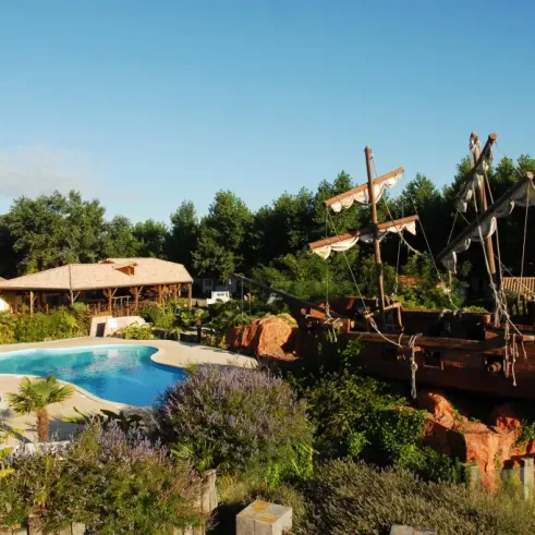 Piscine entourée d'une structure de bateau pirate au Camping Village Corsaire