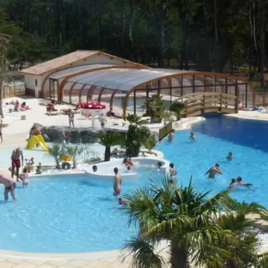 Piscine couverte avec toboggan et personnes nageant au Camping Soulac Plage