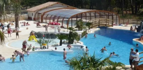 Piscine couverte avec toboggan et personnes nageant au Camping Soulac Plage